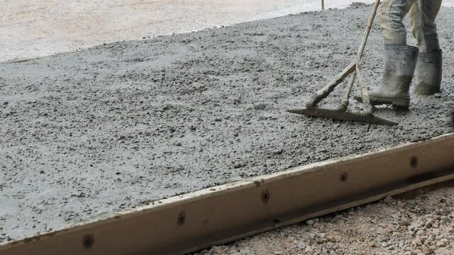 Workers leveling liquid concrete has been poured to concrete slab for construction road.
