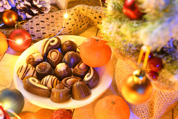 sweet food top view background for merry christmas or new year holiday decoration with night illumination - chocolate candies, tangerines, cookies on white wood