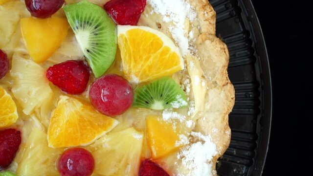 Top view of cake with fresh fruits and ripe berries with cream rotates on tray. Food dessert background. Bakery and pastry shop concept