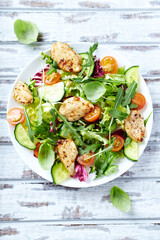 Salad with Chicken Breast, Cherry Tomatoes, Cucumber, Rocket and fresh Basil. Bright wooden background. Top view. 