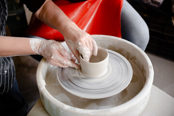 Female hands crafting a pottery cup on a potter's wheel. Handmade and crafting concept.