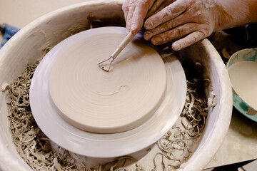 Female hands crafting a pottery cup on a potter's wheel. Handmade and crafting concept.