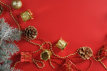 Christmas decorations with spruce branches on a red background with free space.