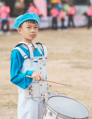 Kids playing music in marching band, cute Asian child hitting drum instrument on sport day in school