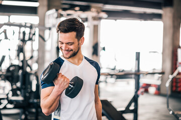 Smiling man exercising with weights in the gym.