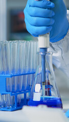 Close up of researcher testing liquid sample using micropipette for new treatment medical...