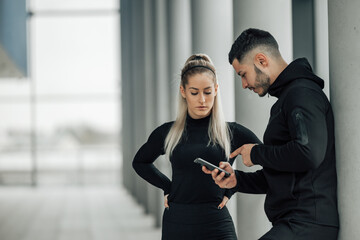 Muscular people, looking at phone.