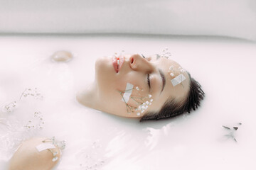 Woman takes a bath with milk and flowers.