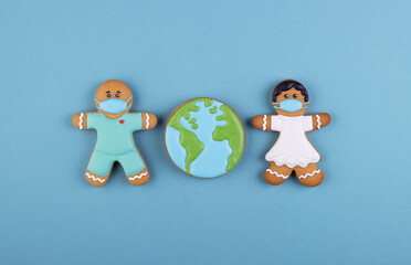 Obraz premium two gingerbread man medics in a mask girl and boy, gingerbread planet earth in the middle