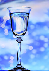 A glass of wine against a background of frosty patterns and sparkling lights. Holiday atmosphere