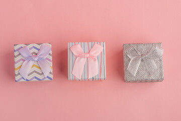 Three little gift boxes on pink background, top view
