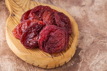 Dried apricots on wooden board, brown background, healthy concept.