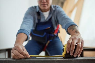 Close up of female construction worker holding tape measure while building metal frame, focus on foreground, copy space