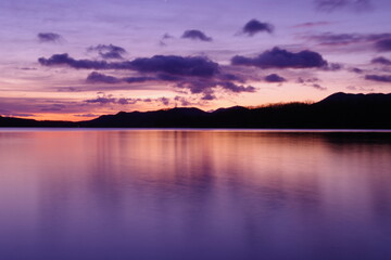 Fototapeta premium 鮮やかなグラデーションの空に浮かぶ雲。湖面に映る黄昏の空が美しい明媚な風景。