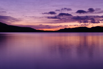 鮮やかなグラデーションの空に浮かぶ雲。湖面に映る黄昏の空が美しい明媚な風景。