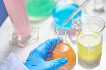 lab technician wearing blue gloves doing experiments and tests in a lab with different colored substances