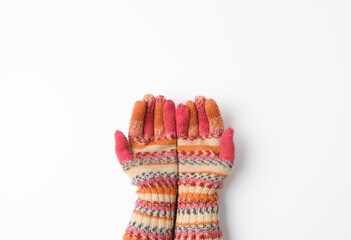 two female joined palms in knitted multi-colored mittens on a white background