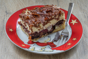 Saftige Donauwelle mit Schokolade, angerichtet mit Kuchengabel auf einem weihnachtlichen Teller mit Bärchen und Sternen