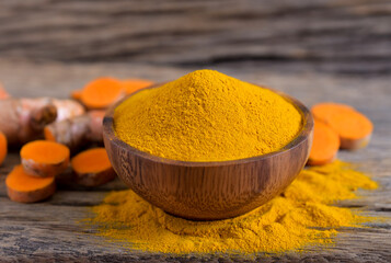 Turmeric (curcumin) powder and fresh turmeric rhizome on a wooden background,For cooking ,spices.
