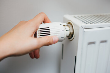 Close up shot of Caucasian female's hand adjusting home radiator temperature using thermostat