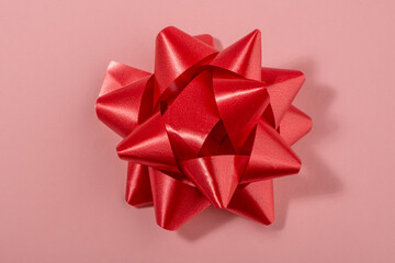 Red bow decoration on pink background, top view