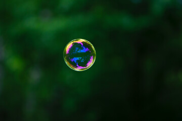 Soap bubble. Isolated on green, in spring or summer. Reflections, reflex. Very detailed, close-up. multi-colored ball flies. holiday concept, childhood