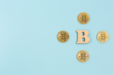 Bitcoins next to wooden B letter on blue background with copy space. Bitcoins and the new concept of virtual money.