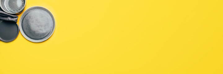 Different gray empty ceramic plates on yellow background, trendy colors 2021, banner size, Top View, Copy Space