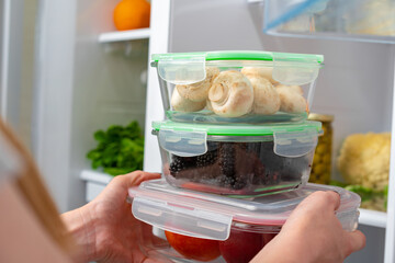 Female hands taking storage box with food from a fridge