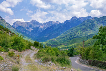 Fototapeta na wymiar Summer landscape - valley and road in Albanian mountains, green trees and gray clouds on the sky