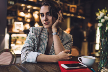 Beautiful female sitting in cafeteria with cup of coffee