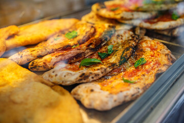 Ripieni al forno con mozzarella e prosciutto in una vetrina di una pizzeria da asporto