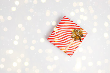 Minimal product frame background for Christmas, New year and sale event concept. Gift box with gold bow on white board with festive golden glitter. Flat lay, top view