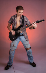 Fototapeta premium Young guitarist play music on his electric guitar with bright emotions. 
