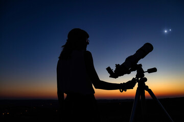 Woman looking at night sky with amateur astronomical telescope.