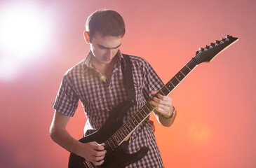 Young guitarist play music on his electric guitar with stage light.