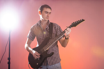 Young guitarist play music on his electric guitar with stage light.