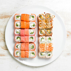 Asian cuisine. Large set of sushi rolls on a plate. Top view. On a white background.