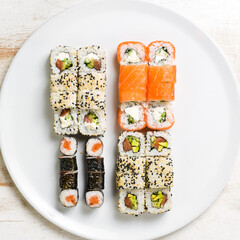 Asian cuisine. Large set of sushi rolls on a plate. Top view. On a white background.