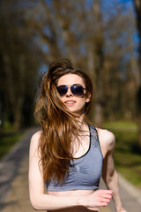 Beautiful athletic girl in sport clothes and glasses on the playground. Soft selective focus.