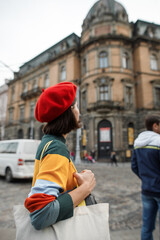 Fototapeta na wymiar young woman in a red beret dressed in parisian style walks the streets of the old city