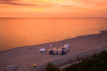 Tents on the Baltic Sea beach during sunset, view from drone