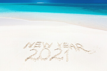 Handwritting inscription word NEW YEAR and number 2021 on perfect tropical sandy beach