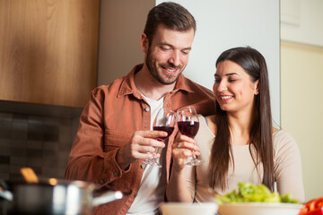 Young man and woman tasting wine while cooking together