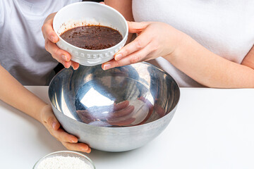 Mom and kid son kneading dough for sweet pastries, cookies. Cooking dough for baking in home kitchen. Preschooler skills, little helper. Family pastime. Adding ingredients/