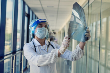 young nurse in a protective suit and face shield checking chest xray image, covid19