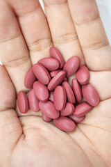 A man with several red pills on his hand As a drug to help treat the patient's condition White background