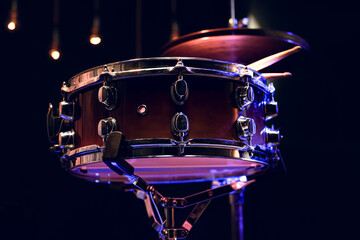 Snare drum and drumsticks close up in dark.
