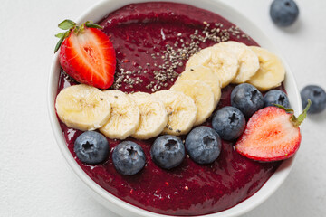 Blueberry smoothie, banana, chia seeds, fresh strawberries in bowl. Eating healthy breakfast bowl. Clean eating, dieting, detox, vegetarian, vegan food concept.