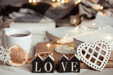 Fototapeta na wymiar Cozy home composition with decorative word love on blurred background with bokeh.